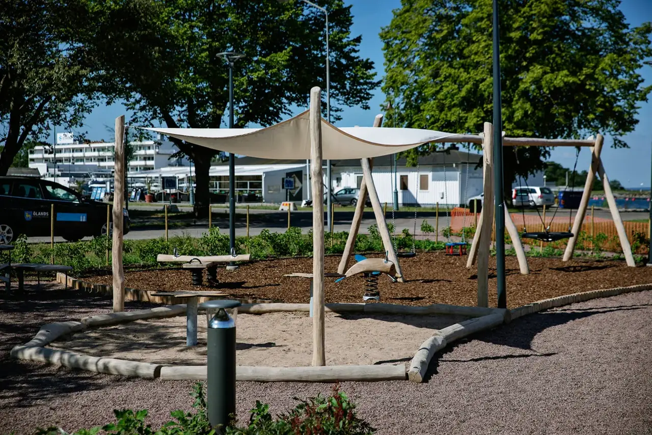 Parasol triangulaire avec voile d'ombrage sur trois poteaux en bois de robinier, exemple proposé par KOMPAN