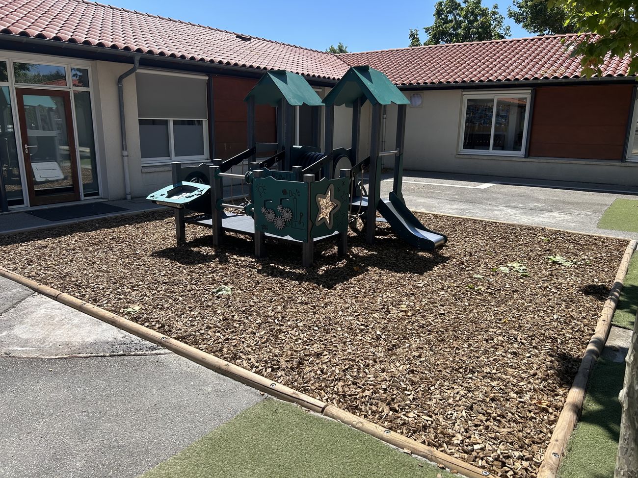 Jeu pour enfants sur sol amortissant en copeaux dans une cour d'école à Cahors